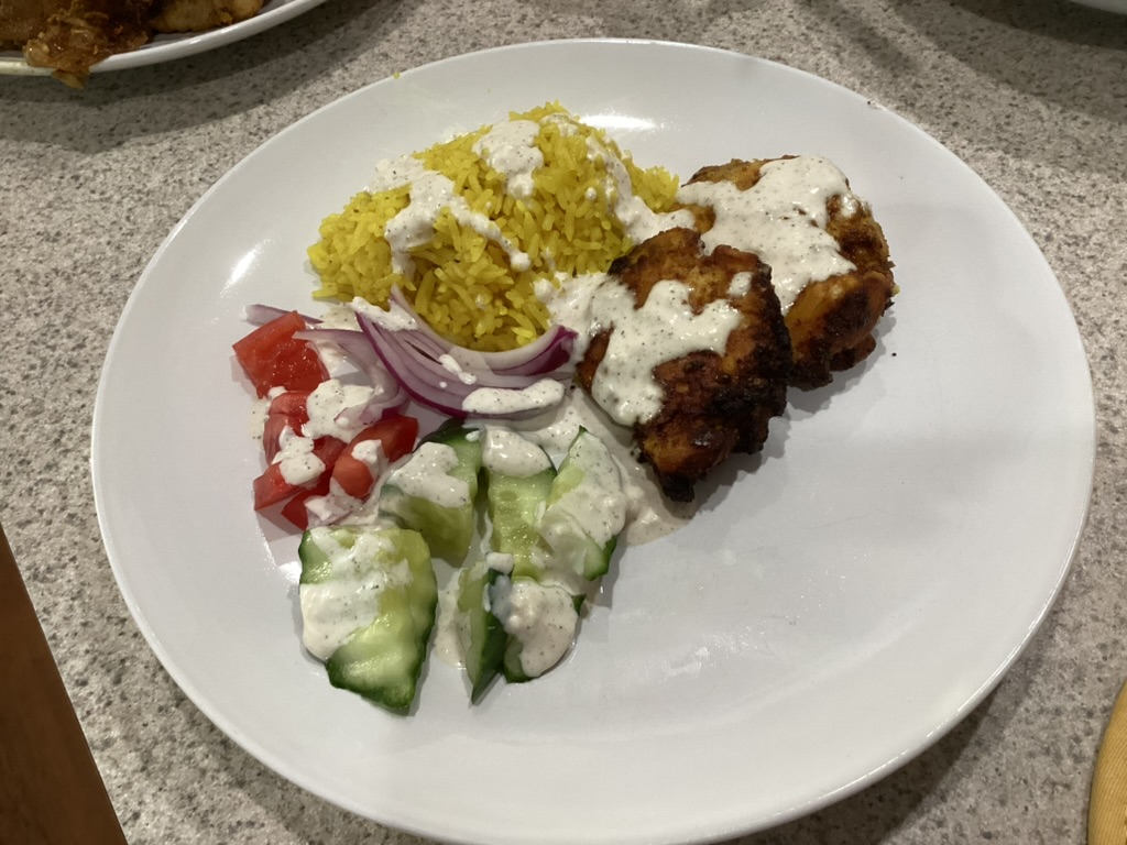 Creamy garlic yogurt dressing served over chicken, yellow rice, and fresh vegetables