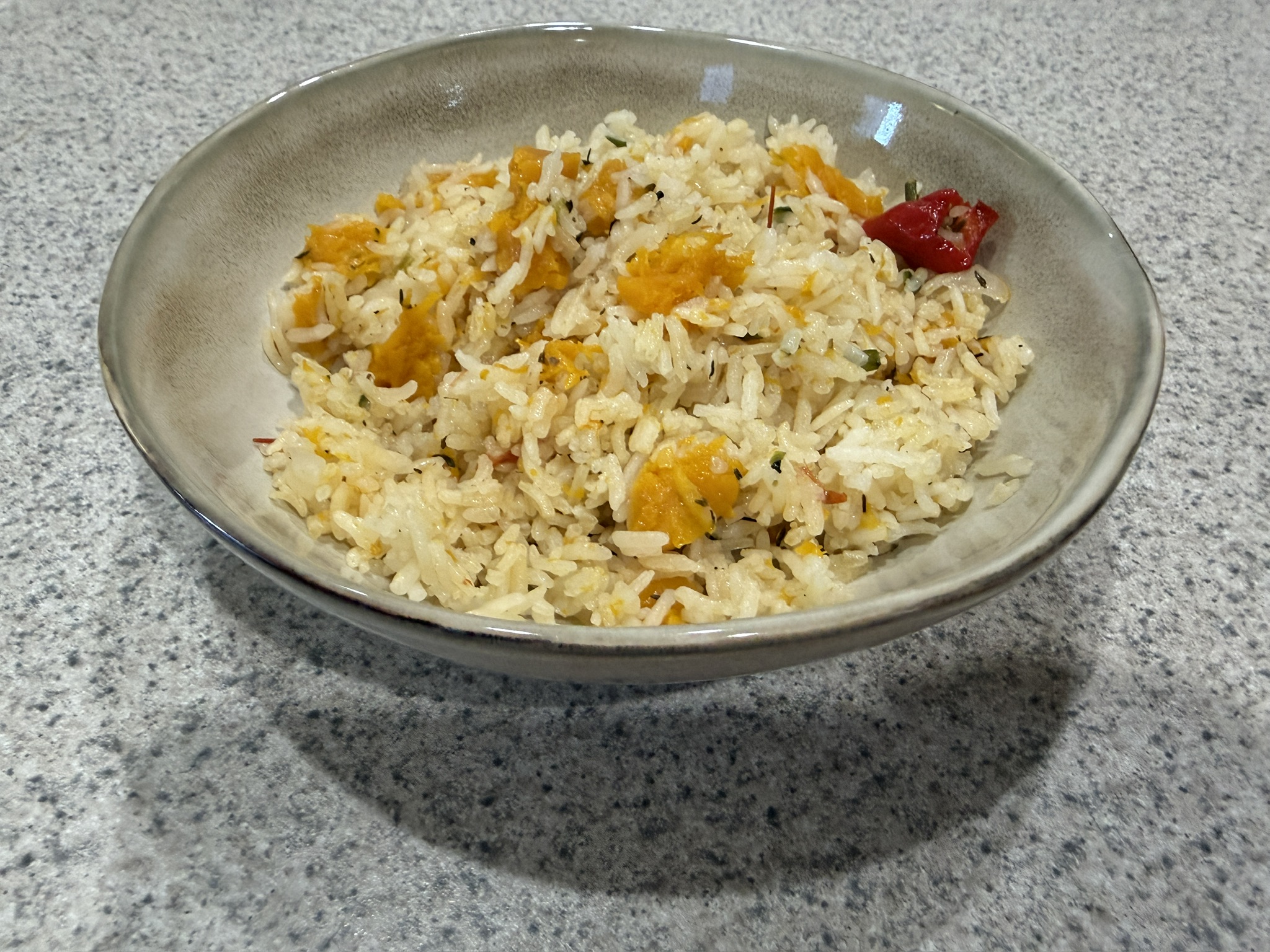 Jamaican pumpkin rice with tender pumpkin pieces and a Scotch bonnet pepper in a bowl
