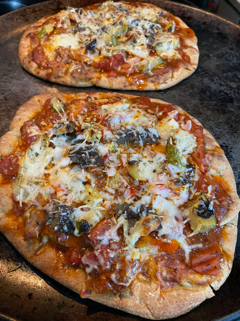 Two homemade naan flatbread pizzas with colorful toppings